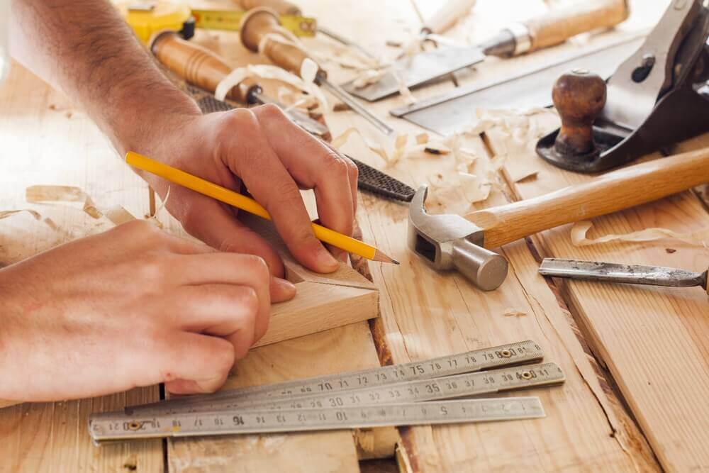 close up image of a handyman Mandurah worker putting together the corner of a picture frame with wood shavings everywhere and some tools close by